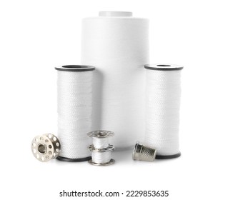 White sewing thread spools and bobbins with a thimble, essential tools for tailoring and textile crafts