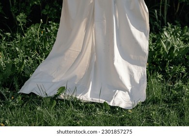 White sheet hanging and drying on a tree above green lush grass. Spring nature background. Concept of boho style. - Shutterstock ID 2301857275