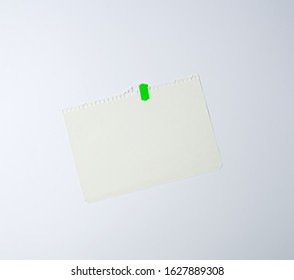 White Sheet Of Paper Torn From A Spiral Notebook And Glued With Green Electrical Tape On A White Background, Place For Text