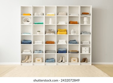 White shelving unit with stacks of different clothes and decor