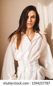 White shirt featuring long puff sleeves with cuffs and a button-up front and leather corset in trendy minimalistic style. Attractive woman shows her skinny shape. Sexy sensual girl.