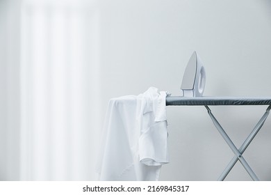 White shirt and iron on ironing board - Shutterstock ID 2169845317