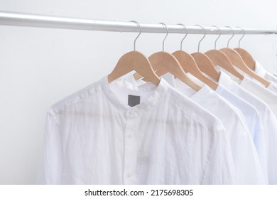 white shirt with t-shirt clothes on wooden racks in closet. Collection of clothing on hangers, - Powered by Shutterstock