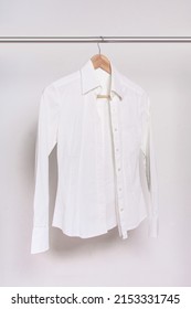 White Shirt And Wooden Hanger On A Rack After Dry-cleaning On Light Background. Vertical Photo.