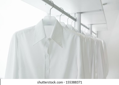 chemises blanches accrochées à un rack dans un placard intégré