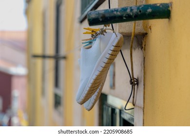 White Shoe On The Washing Line In City With Cement Wall As Background, Hanging Clothes On The Clothesline Outside Building, Typical Portuguese Style Drying Laundry Under The Sun In Summer, Portugal.