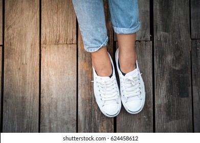 White shoes,Fashion woman's legs with sneakers seated on Wooden floor - Powered by Shutterstock