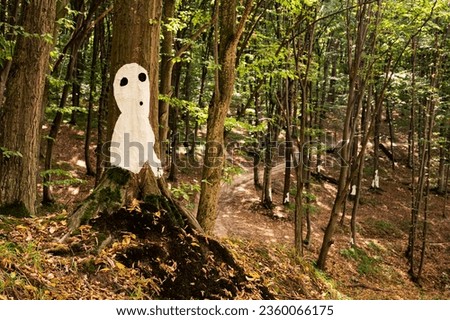 White silhuette of man or alien pictured on tree in forest, covered with yellow dry leafs, with another such silhuettes on background. Scenic, beautiful, mistic, postcard view, wallpaper, Vinnytsia, U