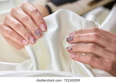 White Silk In Female Manicured Hands. Young Womans Hand With Fresh Manicure Holding Silk Fabric. Concept Of Tenderness And Womanhood.