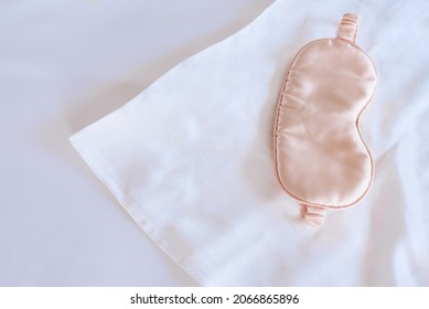 White Silk Pillowcase On The Bed With A Sleep Mask. View From Above
