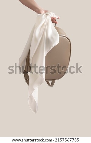 White silk scarf on backpack in the hand isolated high quality image on beige background ideal for creating mockup for presentation own textile design and seamless pattern
