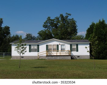 White single-wide mobile residential low income home with vinyl siding on the facade.