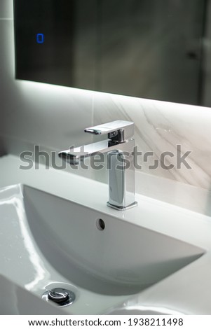 White sink in a modern bathroom with water tap and mirror