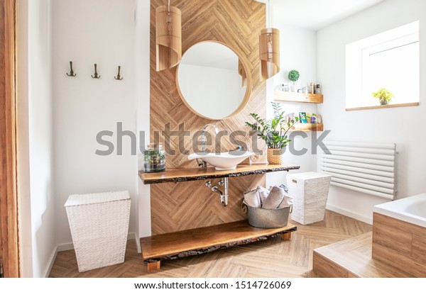 White sink on wood counter with a round mirror\
hanging above it. Bathroom\
interior.
