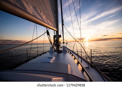 White sloop rigged yacht sailing at sunset.A view of the deck, bow, mast and sails. Baltic sea, Latvia. Transportation, nautical vessel, cruise, sport, regatta, recreation, leisure activity