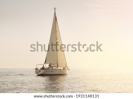 White sloop rigged yacht sailing in the Baltic sea at sunset. Clear sky after the storm, golden sunlight. Transportation, travel, cruise, sport, recreation, leisure activity, racing, regatta