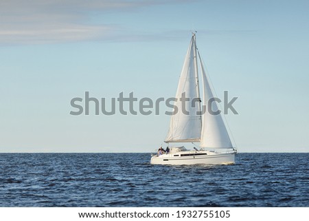 White sloop rigged yacht sailing in the Baltic sea at sunset. Clear sky after the storm, soft sunlight. Transportation, travel, cruise, sport, recreation, leisure activity, racing, regatta