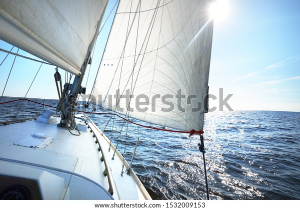 White sloop rigged yacht sailing in an open\
Baltic sea on a clear sunny day. A view from the deck to the bow,\
mast and sails. Estonia