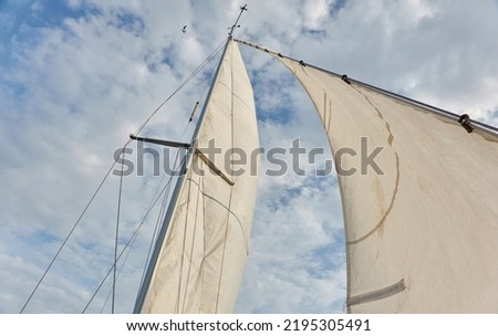 White sloop rigged yacht sails against cloudy blue sky. Sailing in an open sea. Summer vacations, leisure activity, sport and recreation, private wessel concepts