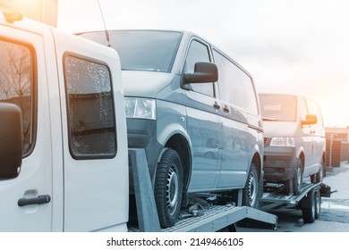 White Small Cargo Truck Car Carrier Loaded With Two Yellow Van Minibus On Flatbed Platform And Semi Trailer Tow On Roadside Highway Road. Volunteer Support Delivery Transport For Ukrainina People