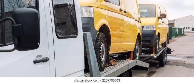 White Small Cargo Truck Car Carrier Loaded With Two Yellow Van Minibus On Flatbed Platform And Semi Trailer Tow On Roadside Highway Road. Volunteer Support Delivery Transport For Ukrainina People