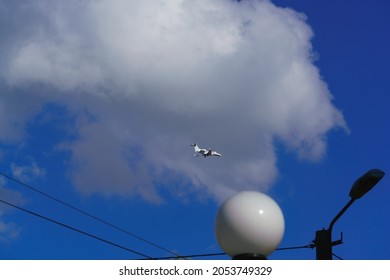 White Small Jet Plane In Blue Sky With White Clouds On A Sunny Day