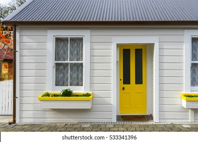 White small wooden house with yellow door