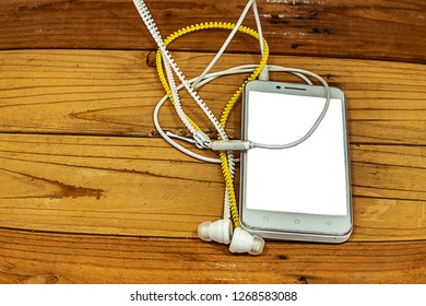 white smart phone with headset on wood table