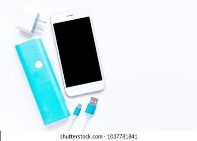 White smartphone with battery bank and charging cables in top view