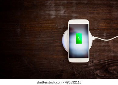 White smartphone charging on a charging pad. Wireless charging