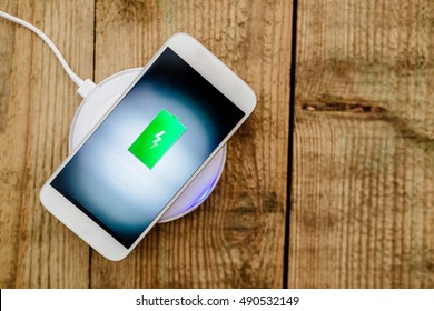 White smartphone charging on a charging pad. Wireless charging