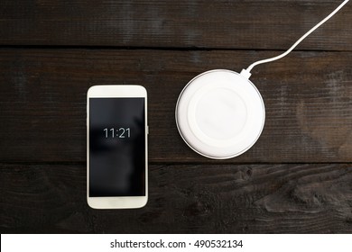 White smartphone and charging pad. Wireless charging