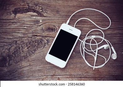 White Smartphone With Headphones On An Old Wooden Board