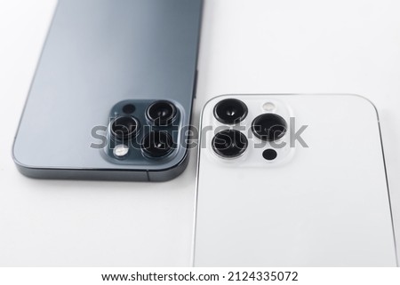 a white smartphone with three cameras lies on a  white background
