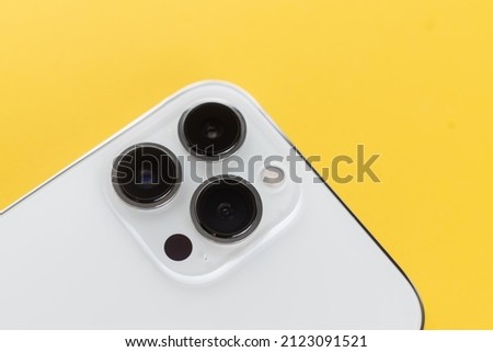 white smartphone with three cameras on a yellow background