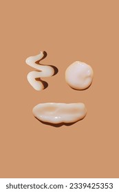 White сosmetic smears of sunscreen creamy texture on a pastel background in the shape of smiley and smiling face. SPF sunblock cream. Natural skin care concept. Cream mockup