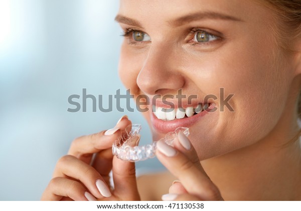 White Smile. Portrait Of Beautiful Smiling Woman\
With Healthy Straight White Teeth Holding Teeth Whitening Tray,\
Girl Using Dental Whitener. Dental Beauty Treatment Concept. High\
Resolution Image