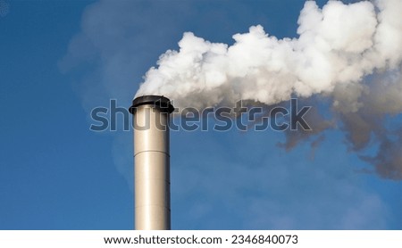White smoke being discharged from a factory chimney into the sky