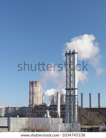 White smoke comes from a white chimney heat station pipe on a blue sky background. The environment. Greenhouse effect.