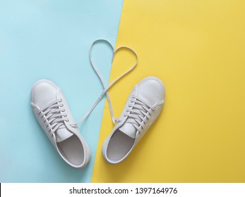 white sneakers with laces in heart shape. Fashion Trendy Trainers with Heart. Love, Hipster Set. Female sneakers, sport shoes in flat lay style, top view. Fitness, active lifestyle, body care concept