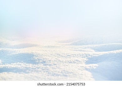 WHITE SNOW IN SUN LIGHT ON LIGHT BLUE FROSTY SKY  BRIGHT WINTER BACKDROP BACKGROUND WITH EMPTY SNOWY FIELD SPACE FOR MONTAGE OR DISPLAY  COLD NATURE LANDSCAPE