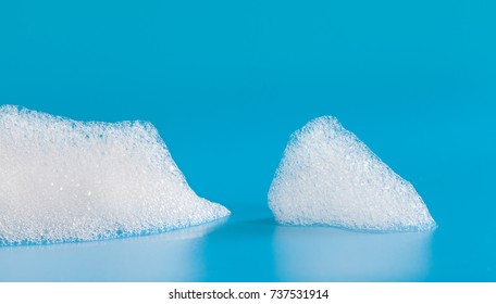 White Soap Bubbles Foam On Blue Background. Suds Shower Texture Macro View Photo, Shallow Depth Of Field