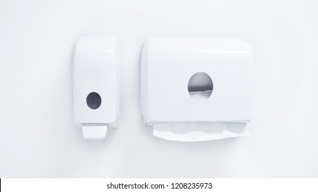White soap dispenser pump and toilet paper towel dispenser on wall in bathroom - Shutterstock ID 1208235973