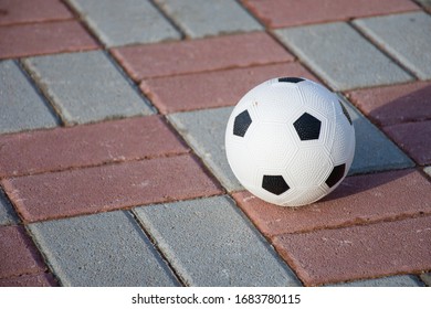 White Soccer Ball On Bricks In The Sunshine. Summer Fun For Kids. Games When Stuck At Home During COVID-19, Coronavirus.