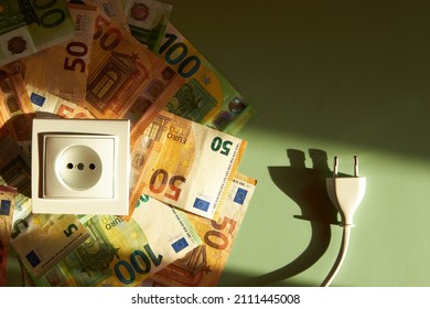 White socket and electric power supply power cords plug with Euro banknotes on green background. Increasing cost of electricity, expensive energy concept