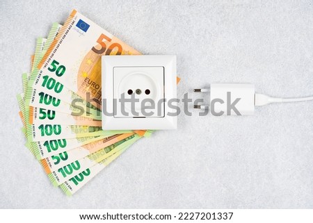 White socket with plug with many Euro banknotes over light background. Concept of increasing prices for electricity in Europe. High energy cost, world and Europe's energy crisis concept