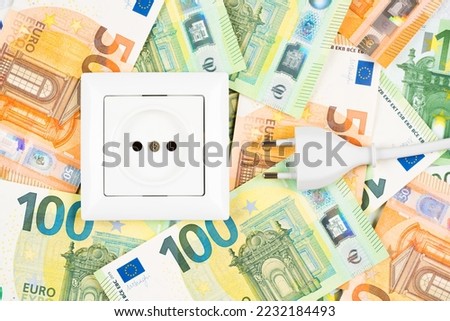 White socket and plug over many Euro banknotes as background. Concept of increasing prices for electricity in Europe. High energy cost, world and Europe's energy crisis concept