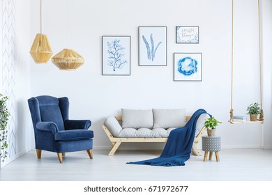 White sofa and blue armchair in living room with posters on the wall - Shutterstock ID 671972677