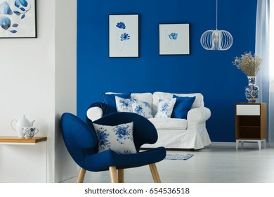 White Sofa And Blue Chair With Flowery Pillows In Cozy Living Room