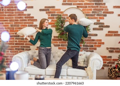 White Sofa. Concept Of Family, Christmas And Winter Season. Couple Have Fun And Do Pillow Fight In Room. Christmas Decor.